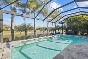 An outdoor swimming pool with clear water, surrounded by palm trees and a view of a body of water. - 3BR/3BA · Private Heated Pool · Gated Resort · Near Venice & Gulf Beaches (Nokomis)
