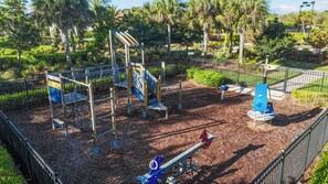 Une aire de jeux avec un toboggan, des structures d’escalade et une balançoire.