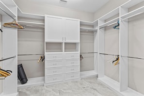 A walk-in closet with white shelving, drawers, and hanging space. - 3BR/3BA · Private Heated Pool · Gated Resort · Near Venice & Gulf Beaches (Nokomis)