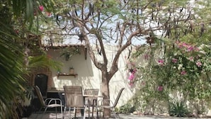 An outdoor patio area with a table and chairs, surrounded by greenery and flowering plants. - Tranquil Cabo Villa w/ Private Pool, Grill & Patio (Cabo San Lucas)