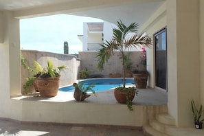 A pool area with potted plants and a view of a building in the background. - Tranquil Cabo Villa w/ Private Pool, Grill & Patio (Cabo San Lucas)