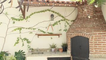 Un patio con un forno a mattoni, piante in vaso e una lampada a sospensione.