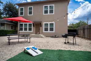 A two-story building with a patio area featuring a barbecue grill, a picnic table, and a red umbrella. - Casa Marina ✨ Spacious 3BR • 1 Mile to Pearl & Downtown (San Antonio)