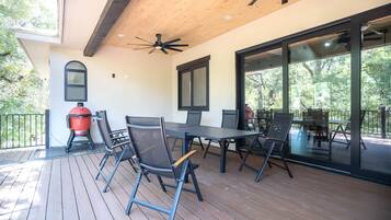 Un patio exterior con cubierta de madera, ventilador de techo y una parrilla.