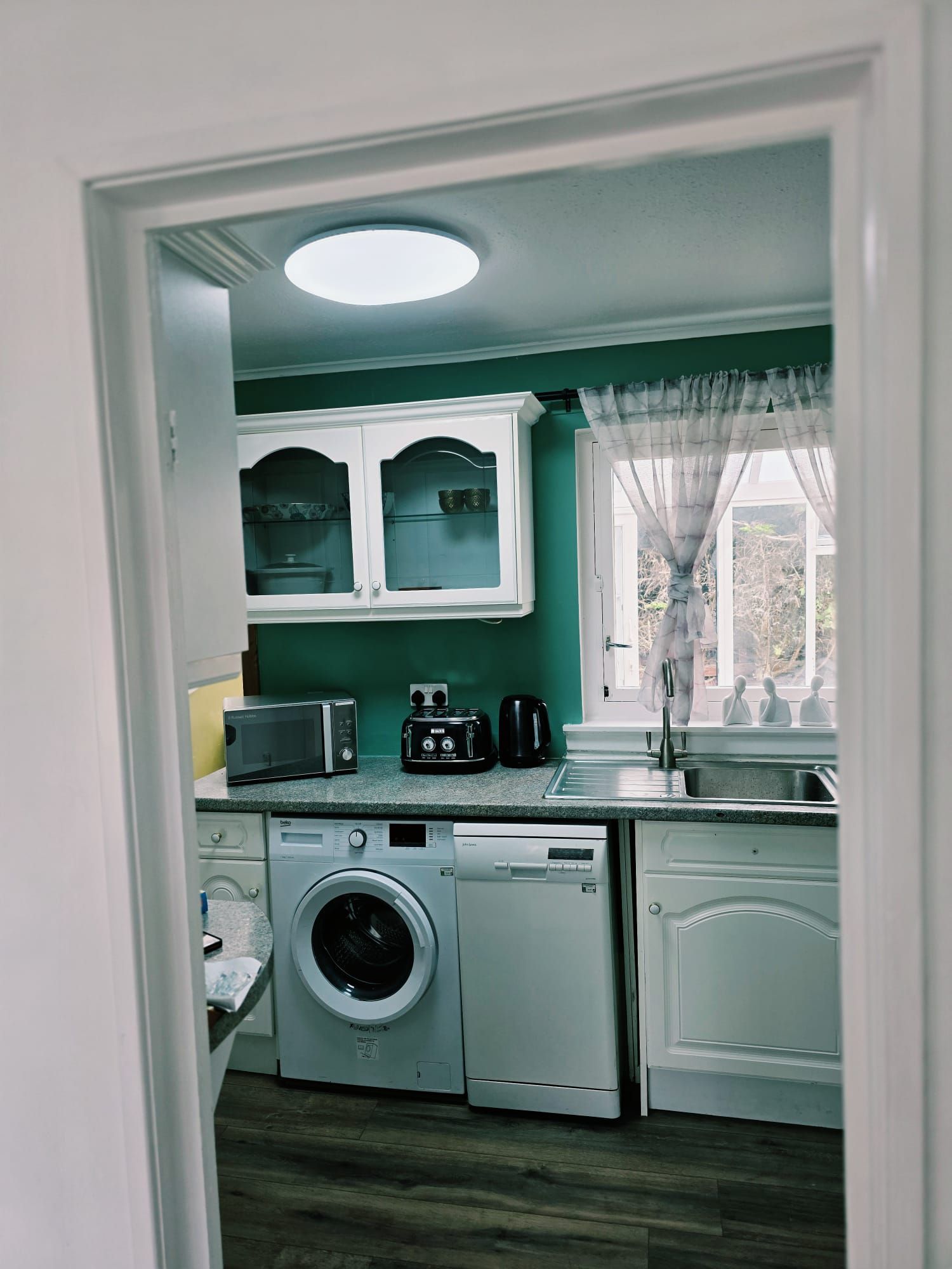 A compact kitchen with a washing machine, a microwave, and a coffee maker.
