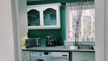 A compact kitchen with a washing machine, a microwave, and a coffee maker.