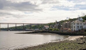 A coastal town with a bridge, stone buildings, and a beach.