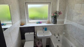 Un baño con inodoro, lavabo, bañera y ventana.