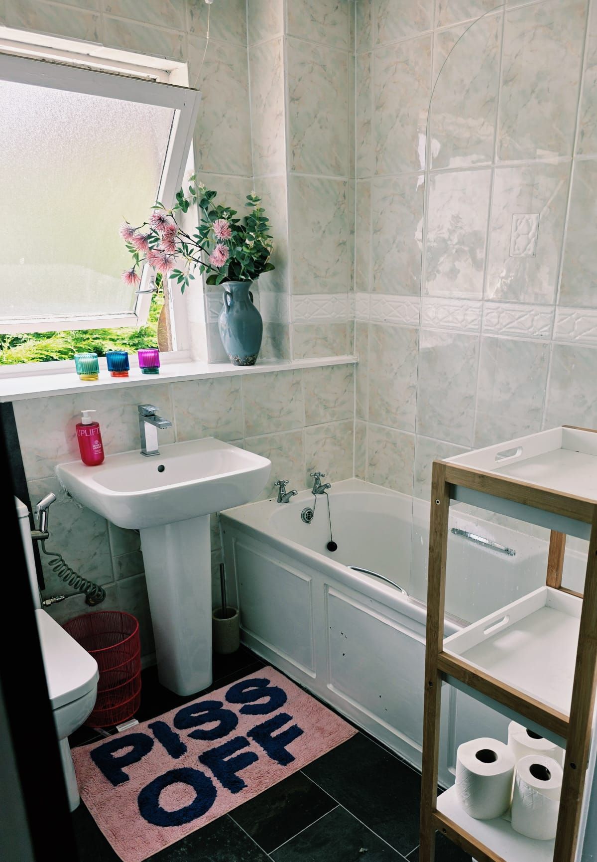 Ein Badezimmer mit Waschbecken, Toilette, Badewanne und Ablagefläche mit Toilettenpapier.