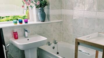 Ein Badezimmer mit Waschbecken, Toilette, Badewanne und Ablagefläche mit Toilettenpapier.