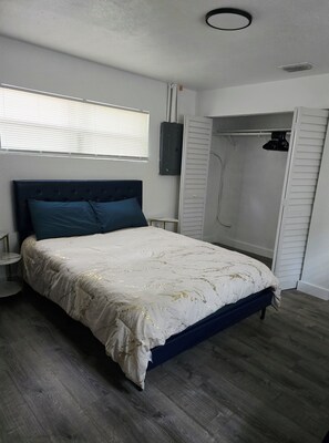 A bedroom with a bed, a nightstand, a wardrobe, and a window with blinds. - Cozy 1-bedroom for rent in pleasant St. Petersburg with AC (St. Petersburg)
