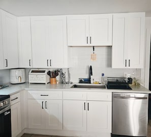 A modern kitchen with white cabinets, a toaster, a coffee maker, and a dishwasher. - Cozy 1-bedroom for rent in pleasant St. Petersburg with AC (St. Petersburg)