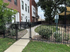 A gated residential area with a pathway leading to a building with a brick facade and white trim. - Downtown Entertainer's Oasis (San Antonio)