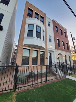 A residential building with a corner entrance, a brick facade, and a black metal fence. - Downtown Entertainer's Oasis (San Antonio)