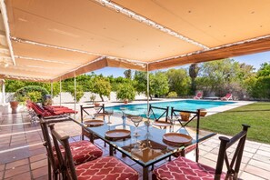 Ein Essbereich im Freien mit einem Pool im Hintergrund.