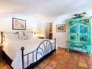 Ein Schlafzimmer mit einem Bett, einem Nachttisch, einer Kommode und einer Wand mit einem gerahmten Bild.