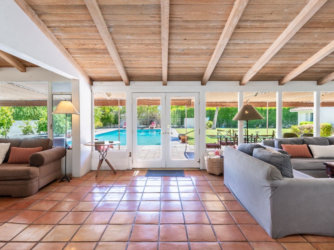 A spacious patio with a pool view, a sofa, and a lamp.