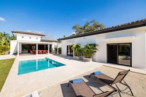 Une maison moderne dotée d’une piscine, d’un espace salon extérieur et d’un patio.