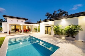 A modern house with a swimming pool, outdoor seating, and potted plants. - 5 Bedroom Villa in Hacienda Pinilla Golf Resort (Hacienda Pinilla)