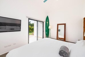 Ett hotellrum med en säng, en tv som är monterad på väggen, en skjutdörr i glas som leder ut till ett utomhusområde och en grön dekorativ detalj på väggen.