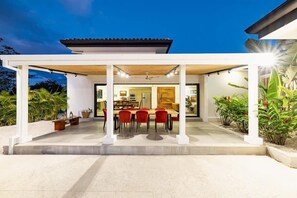 Eine überdachte Terrasse im Freien mit Essbereich, inklusive Tisch und Stühlen sowie einem Deckenventilator.