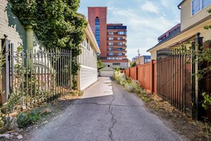 A narrow alleyway flanked by buildings with metal fences and vegetation. - Avenue Nook | Pet Friendly | Grill | Desk (Salt Lake City)