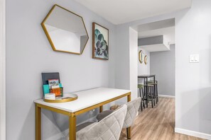 Ein modernes Interieur mit einem weißen Konsolentisch, einer Bank, einem sechseckigen Spiegel und einem gerahmten Kunstwerk an der Wand.