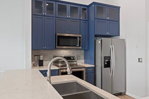 A modern kitchen with blue cabinets, stainless steel appliances, and a marble countertop. - Fully Remodeled "Coastal Luxe" with 1 mile of amazing River Views. Unmatched!! (Crystal River)