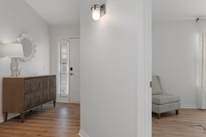 A room with a wooden cabinet, a lamp, a chair, and a door with blinds. - Fully Remodeled "Coastal Luxe" with 1 mile of amazing River Views. Unmatched!! (Crystal River)