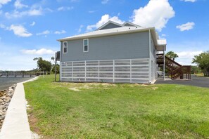 A two-story house with a metal fence in front, a dock, and a clear sky. - Fully Remodeled "Coastal Luxe" with 1 mile of amazing River Views. Unmatched!! (Crystal River)