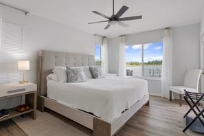 A bedroom with a bed, a nightstand, a chair, a ceiling fan, and a view of the outdoors. - Fully Remodeled "Coastal Luxe" with 1 mile of amazing River Views. Unmatched!! (Crystal River)