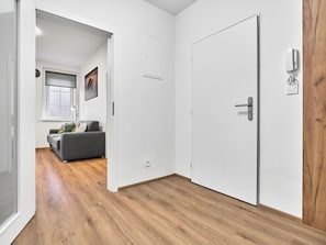 A hallway with a grey sofa, a white door, and a wooden floor. - Mánesova by Interhome (Jachymov)