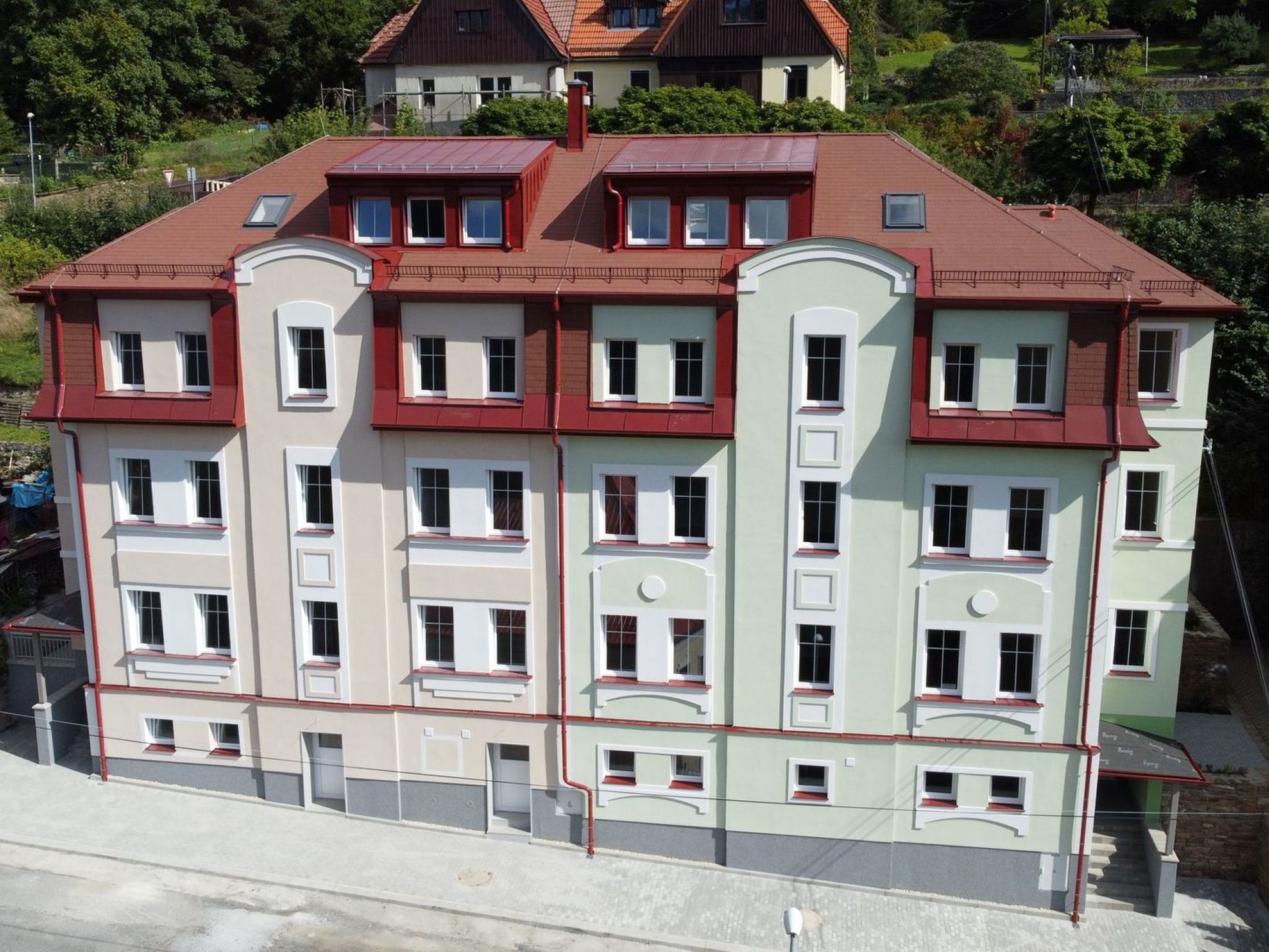 A multi-story building with a red roof, multiple windows, and a balcony.