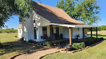 A single-story house with a porch, a covered front entrance, and a gravel driveway.