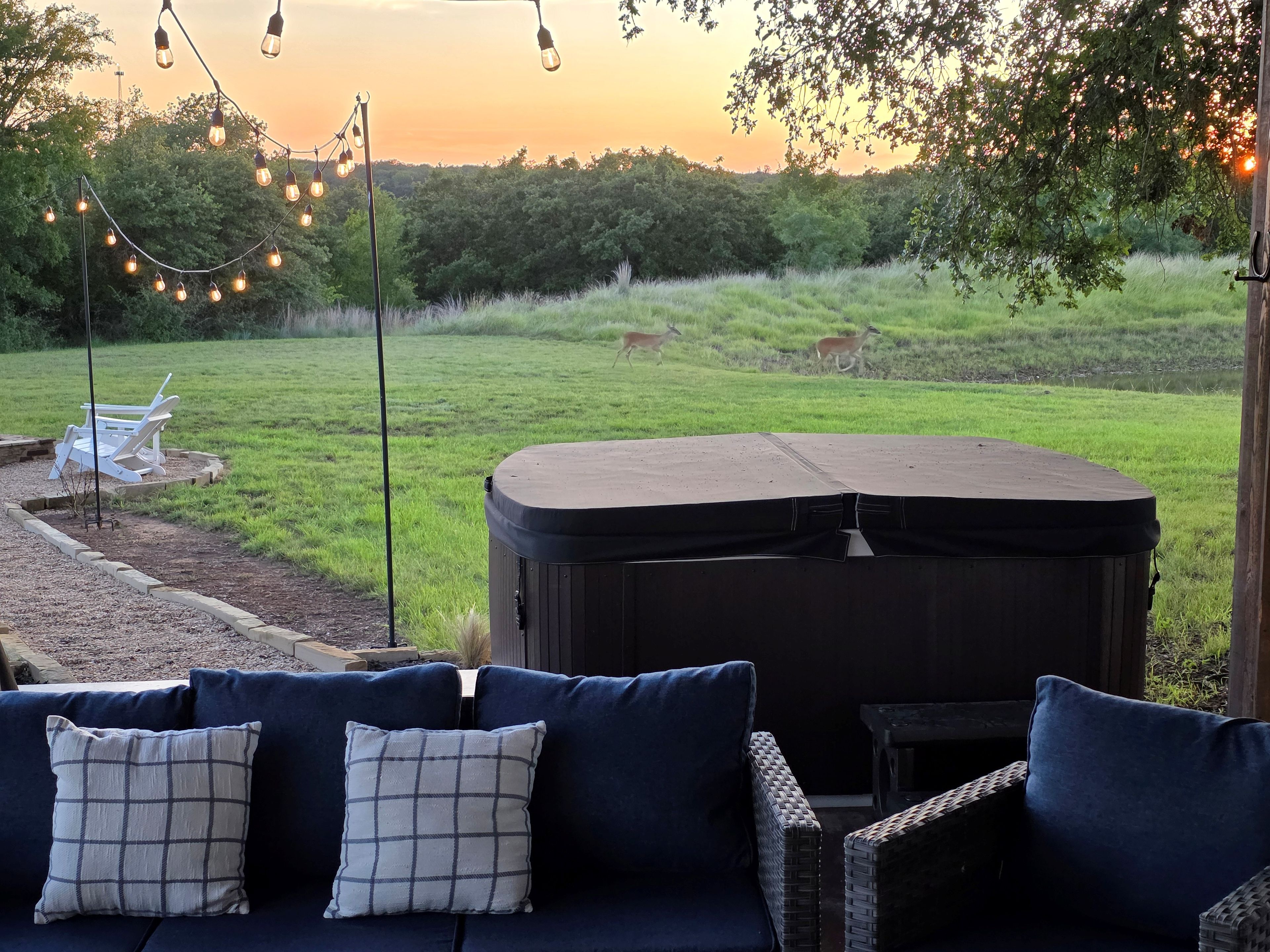 A patio area with a dark-colored outdoor seating arrangement, a hot tub, and a string of lights.