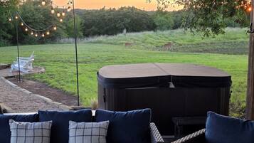 A patio area with a dark-colored outdoor seating arrangement, a hot tub, and a string of lights.