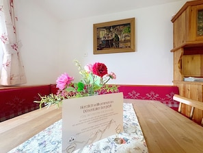 A room with a wooden table, a framed painting on the wall, and a welcome sign. - Dösentaler Bergidyll by Interhome (Mallnitz)