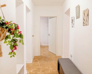 Ein Korridor mit Holzboden, weißen Wänden und einer Tür am Ende.