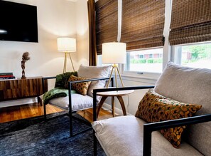 A modern living room with a sofa, armchairs, a coffee table, and a TV mounted on the wall. - Beech Bungalow • Pool • Hot
Tub • Mid-Century Retreat • Midtown Jackson (Jackson)