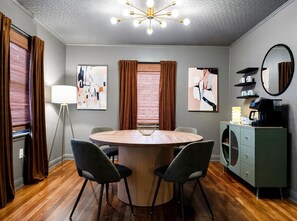 A dining area with a round table, chairs, a floor lamp, and a cabinet with a coffee machine. - Beech Bungalow • Pool • Hot
Tub • Mid-Century Retreat • Midtown Jackson (Jackson)