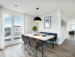 A modern living room with a dining area, large windows, and a city view. - Holiday Apartment With 1 Bedroom (Kappeln)
