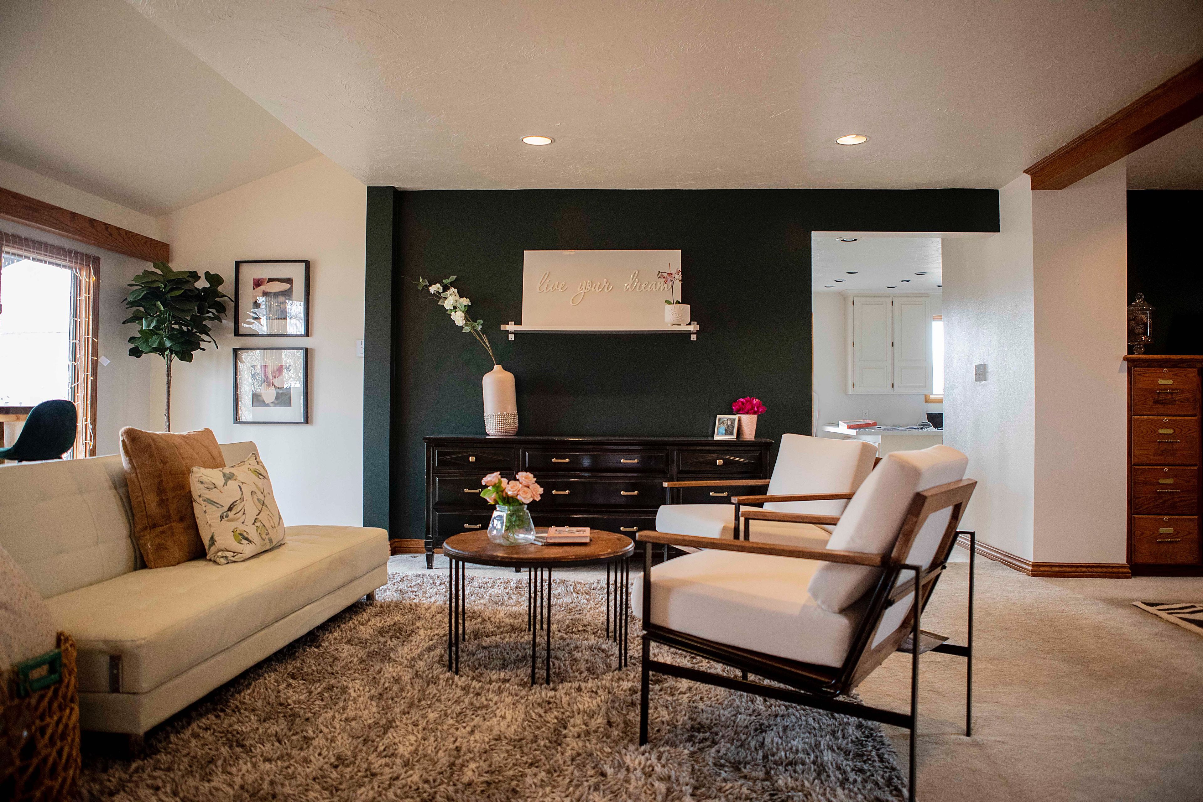A living room with a sofa, chairs, a coffee table, and a dark accent wall.