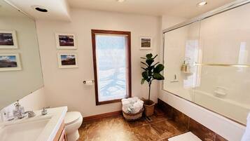 A bathroom with a bathtub, a sink, a toilet, and a window with blinds.