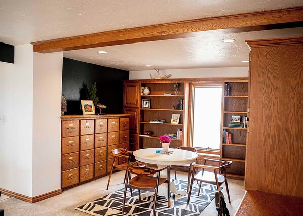 A room with a wooden cabinet, a round table with chairs, and a bookshelf.