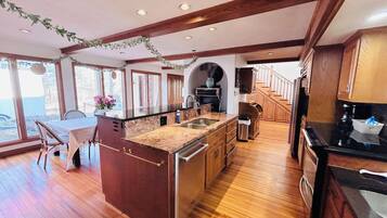 A spacious kitchen with wooden floors, a central island, and a dining area with a table and chairs.