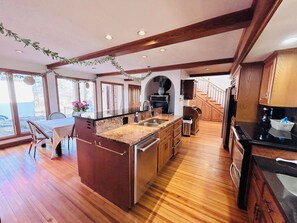 A spacious kitchen with wooden floors, a central island, and a dining area with a table and chairs.