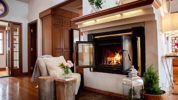 A cozy living room with a fireplace, wooden furniture, and a small Christmas tree.