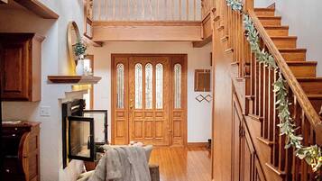Ein geräumiger Flur mit einer Holztreppe, einem Essbereich mit Tisch und Stühlen sowie einer großen Holztür mit Buntglasfenstern.