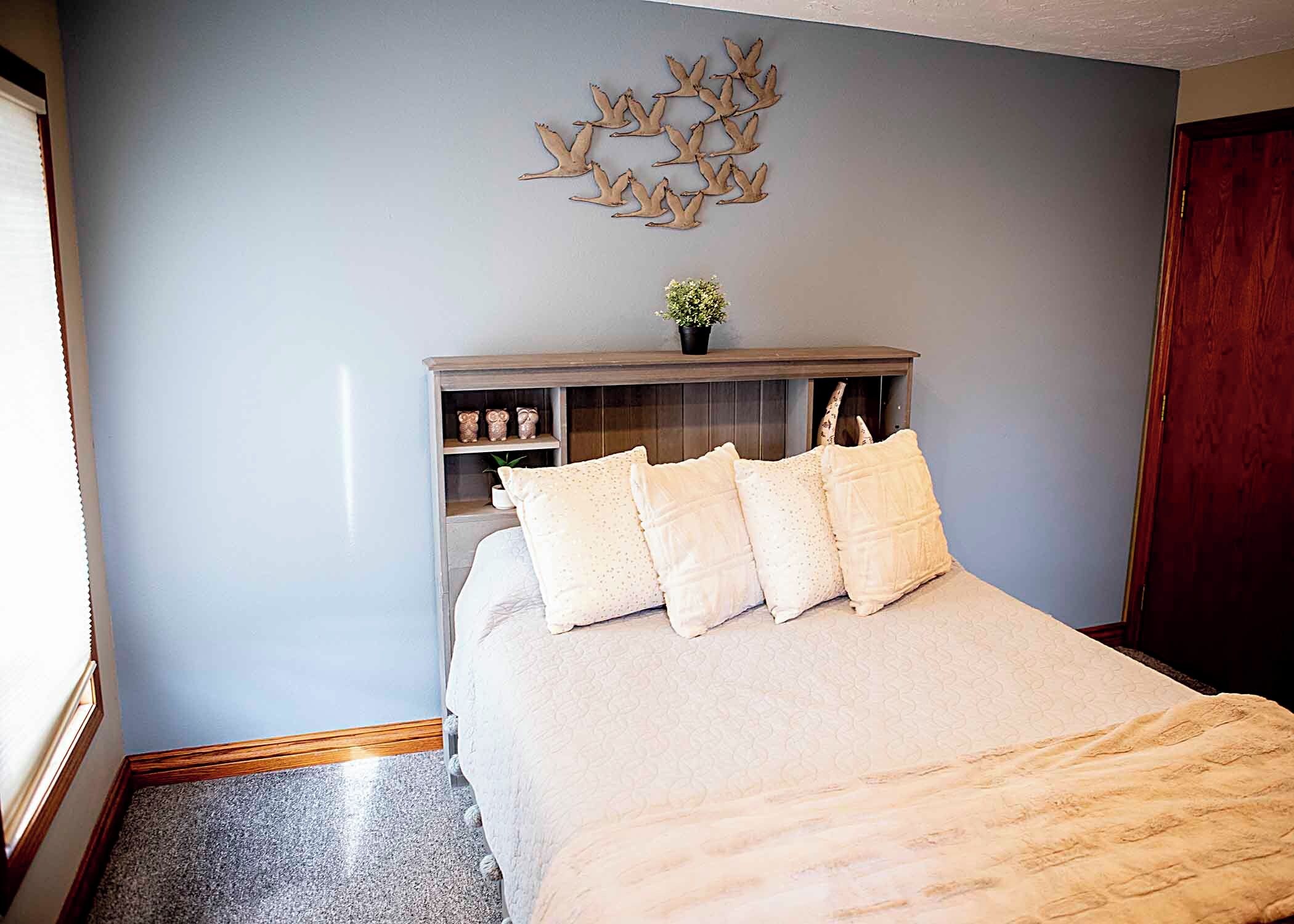 Un dormitorio con cama, mesita de noche, cómoda y decoración en la pared.