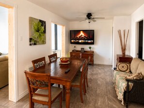 A dining area with a wooden table, chairs, and a television mounted on the wall.